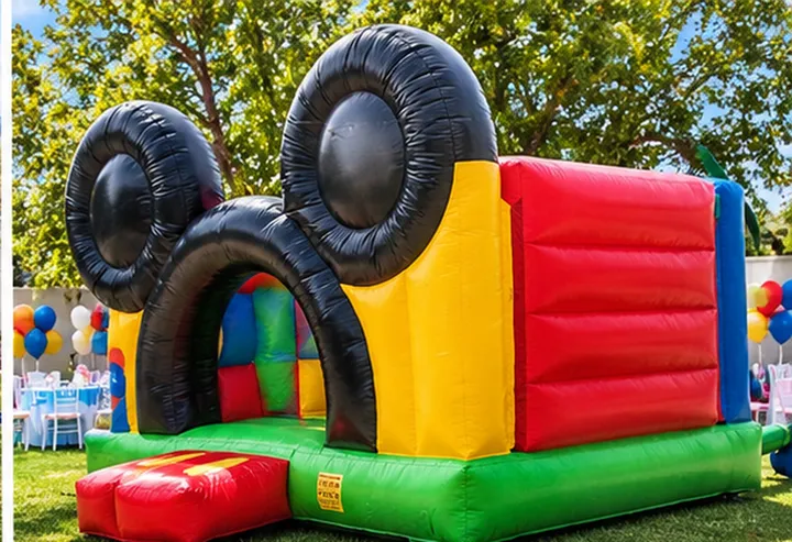 Inflable con orejas de Mickey Mouse en un jardín con mesas decoradas